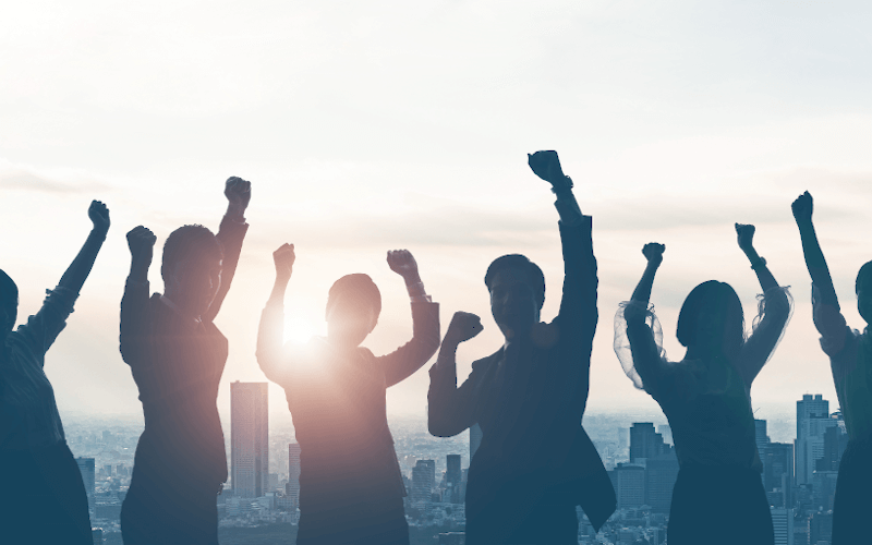 5 Businessleute stehen in Siegerpose vor der darunterliegenden Metropol-Skyline