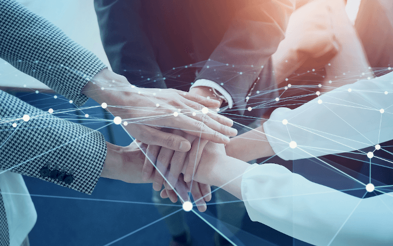 3 Menschen reichen sich partnerschaftlich die Hände